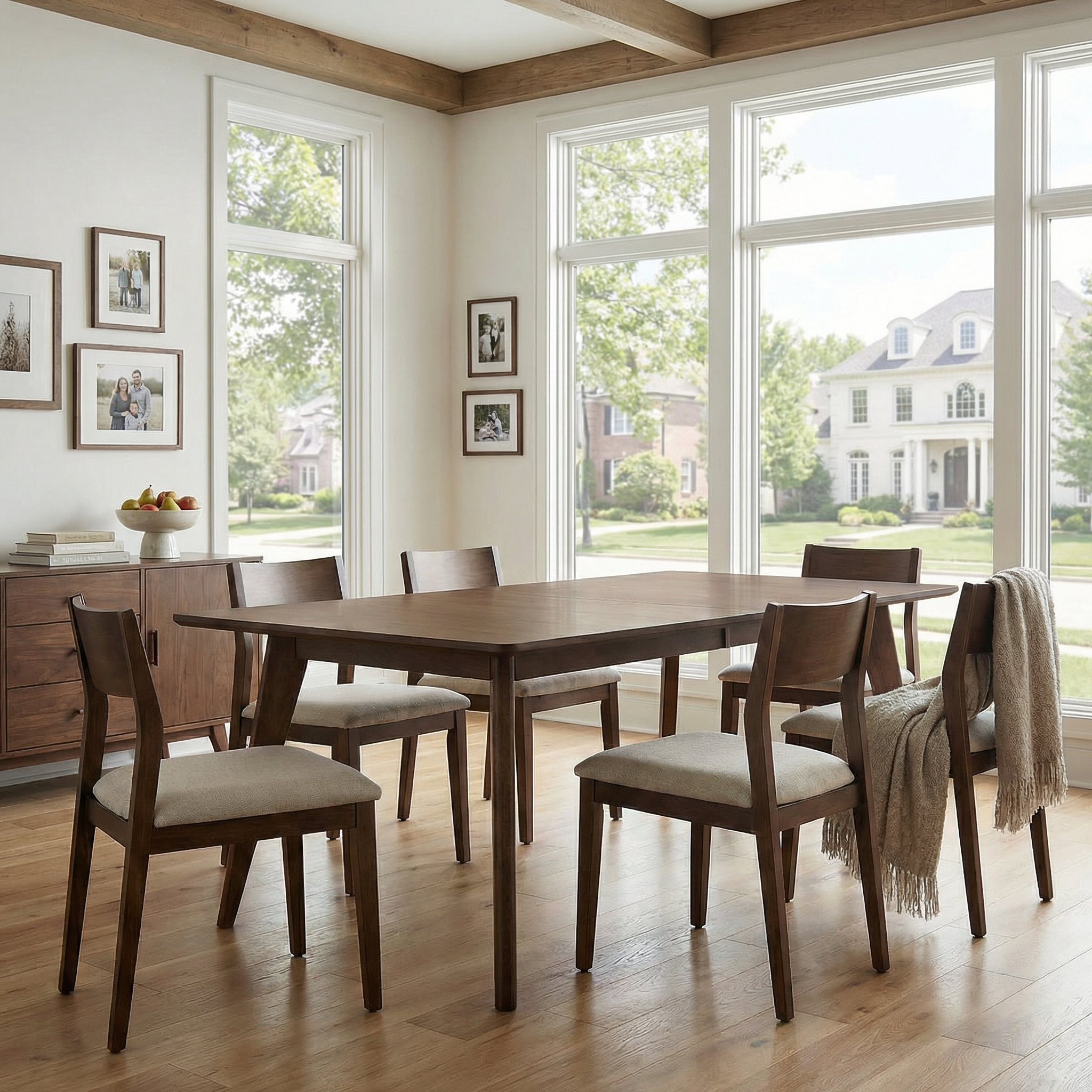 Dining room with wooden table and chairs in a bright room with large windows.