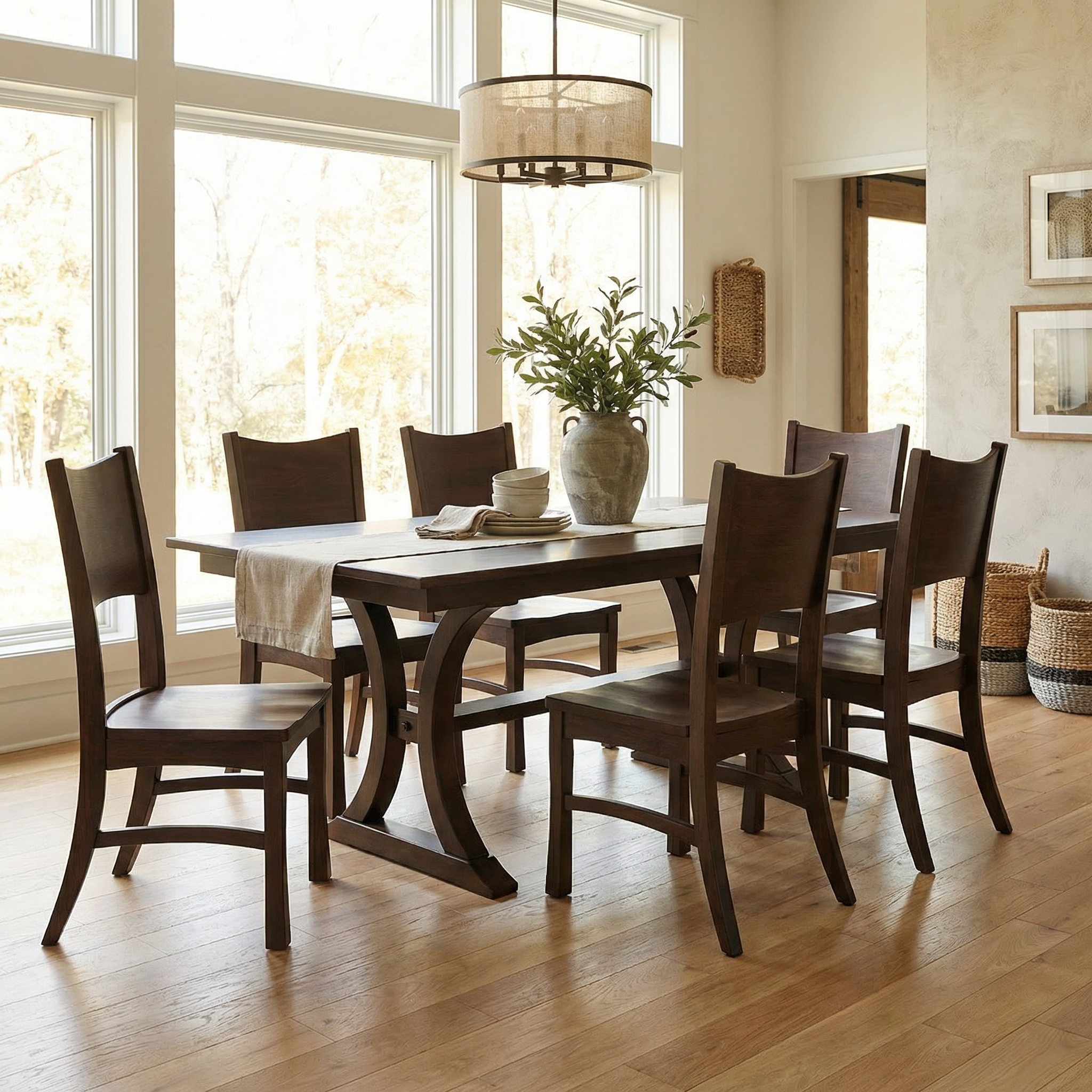 Dining room with wooden table and chairs near large windows.