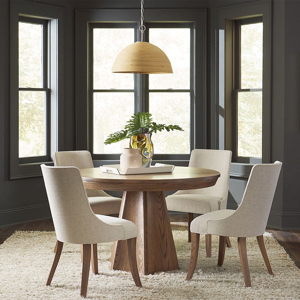Dining room with wooden table and chairs near large windows.